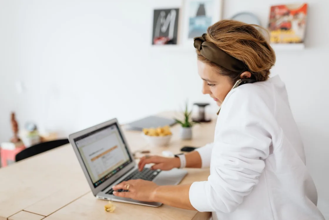 A young recruiter juggling a phone call and candidate profiles on her laptop