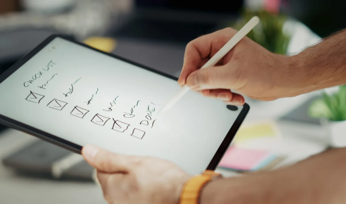 Hand hakt Aufgaben auf einer digitalen Task-Liste am Tablet ab