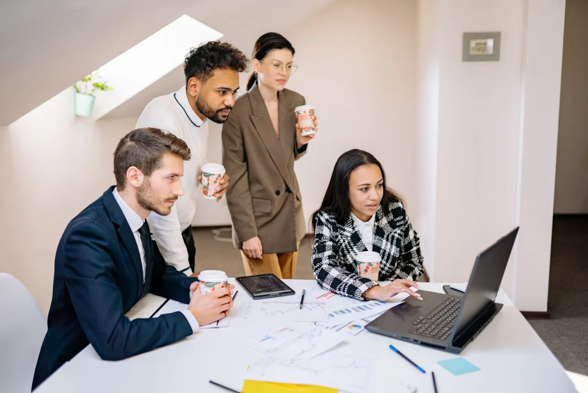 Startup team collaborating around a laptop in a modern office