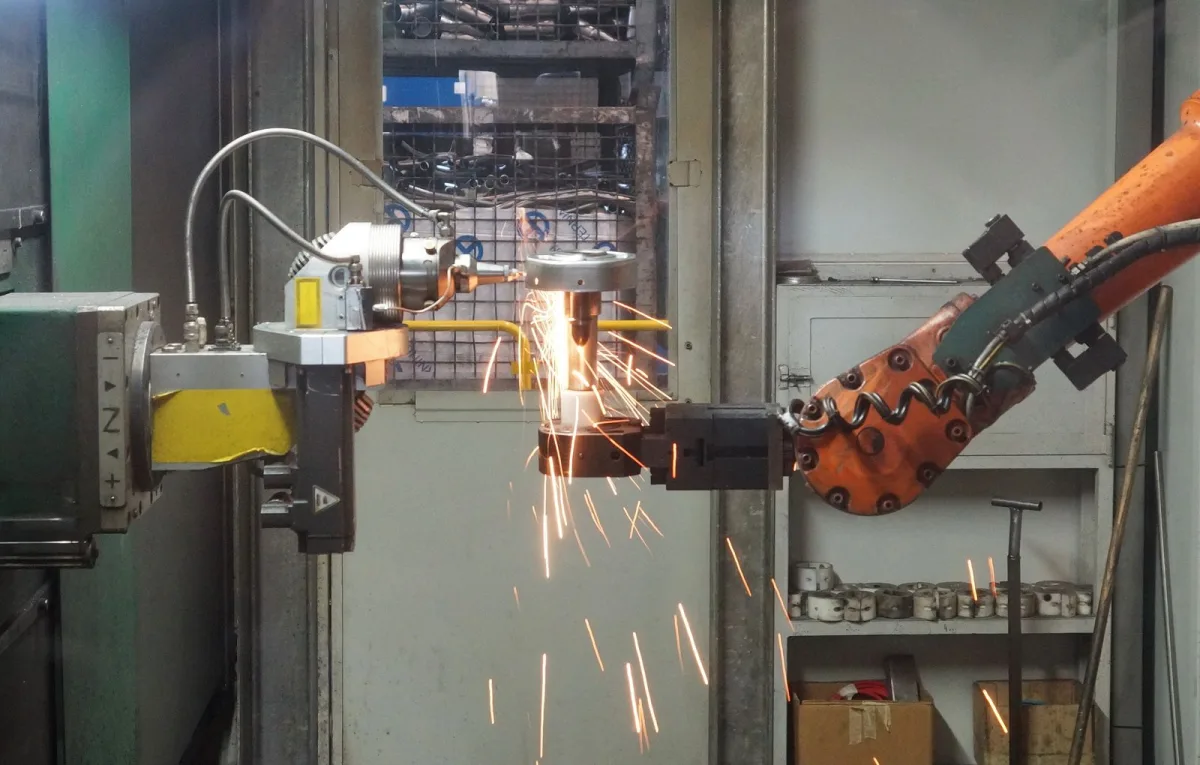 Industrial robot arm working on metal with flying sparks
