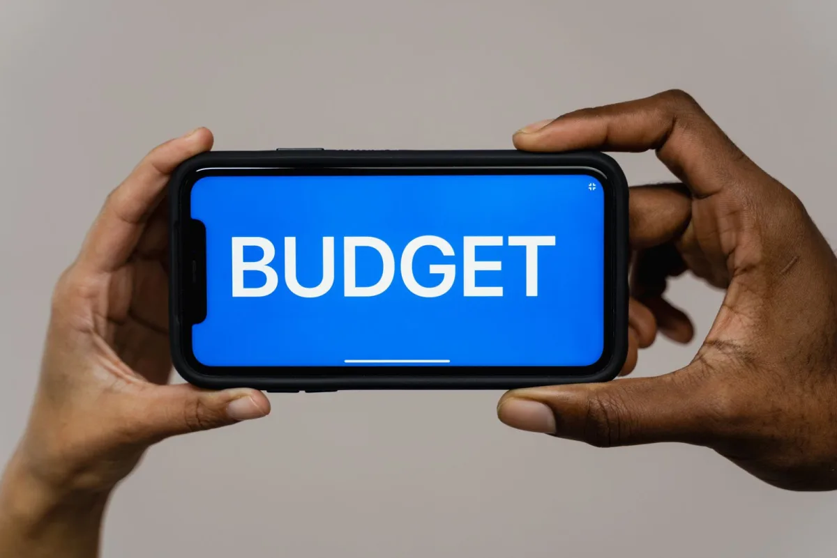 Hands holding a smartphone with a budgeting app on screen