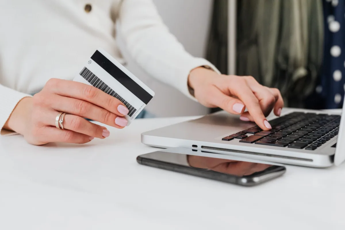 Freelancer holding a business debit card while working on a laptop