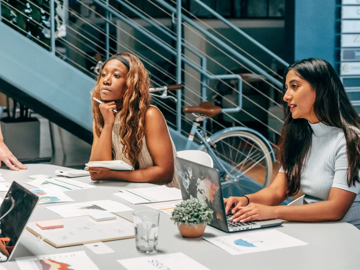 Creative team collaborating over laptops and documents at a shared desk