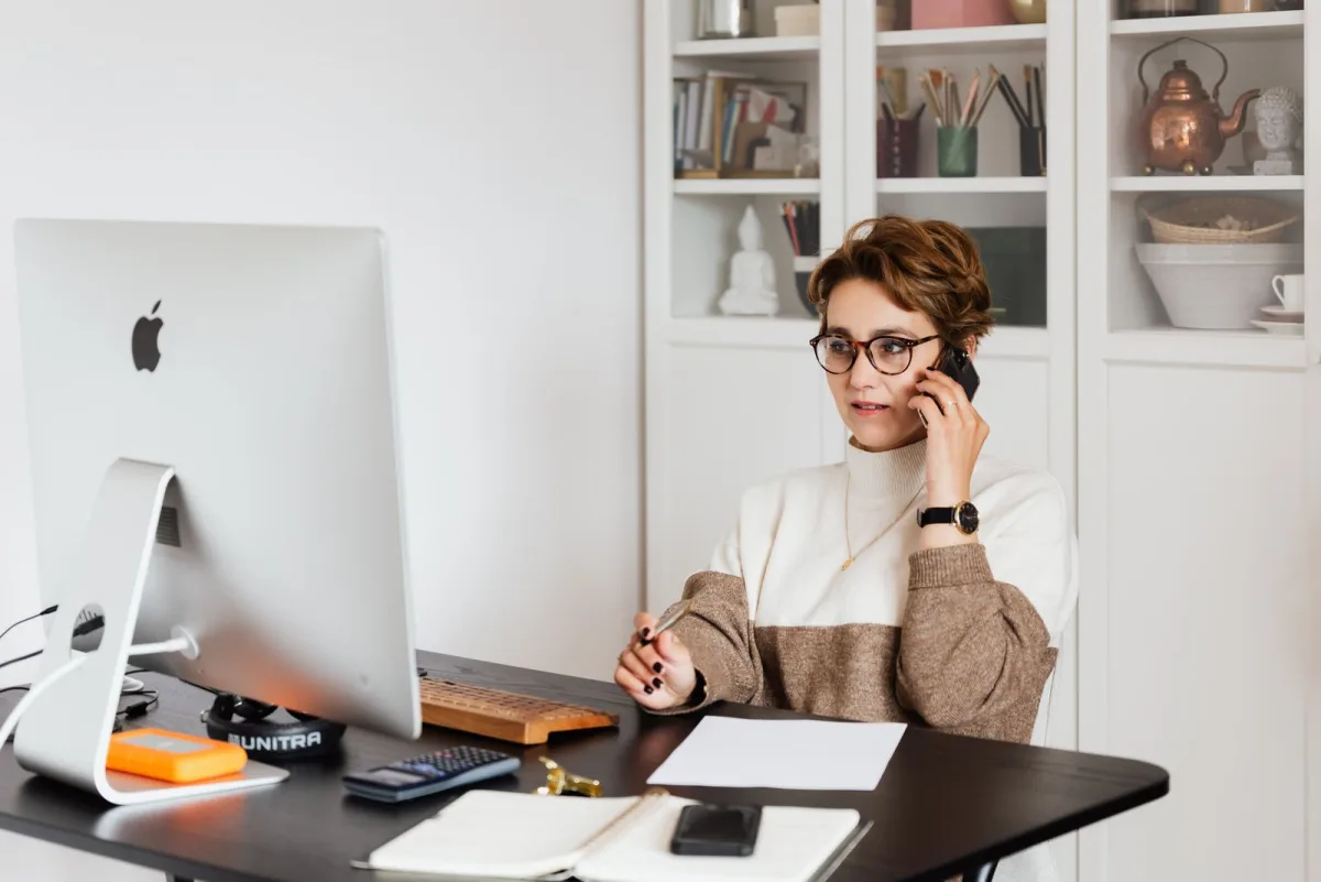 Solopreneur taking a client call at her desk in a small office