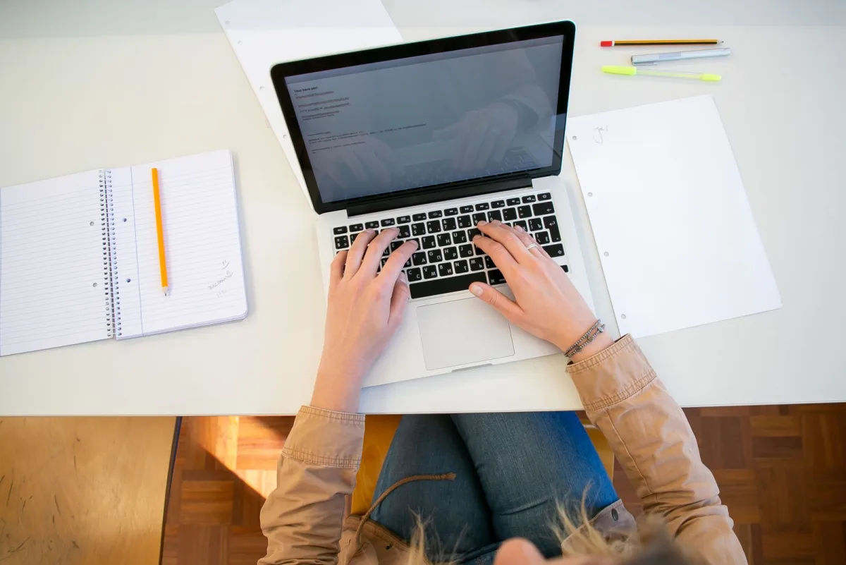 Freelancer preparing invoices on a laptop with documents at her desk