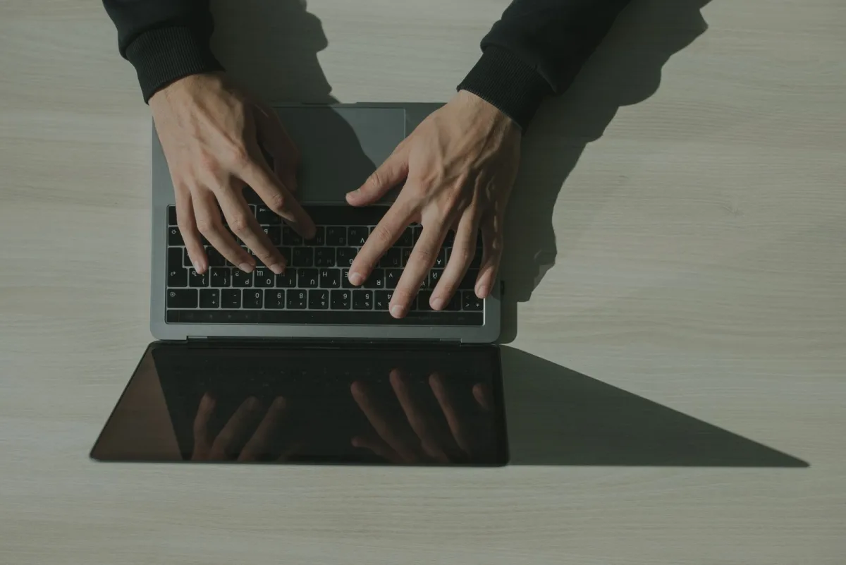 Hands typing on a laptop keyboard