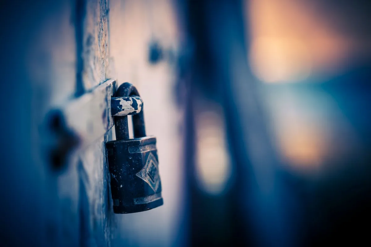 Weathered padlock on a door in moody blue light