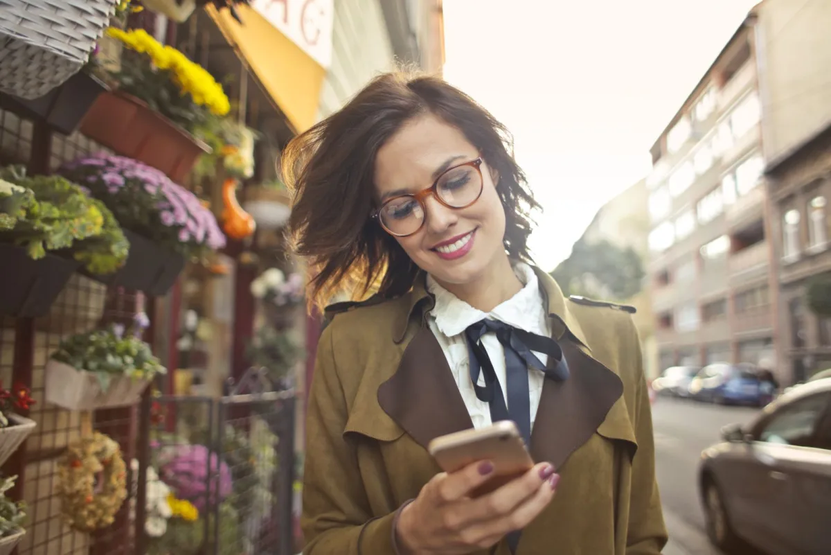 Flower shop owner using her smartphone outside the store