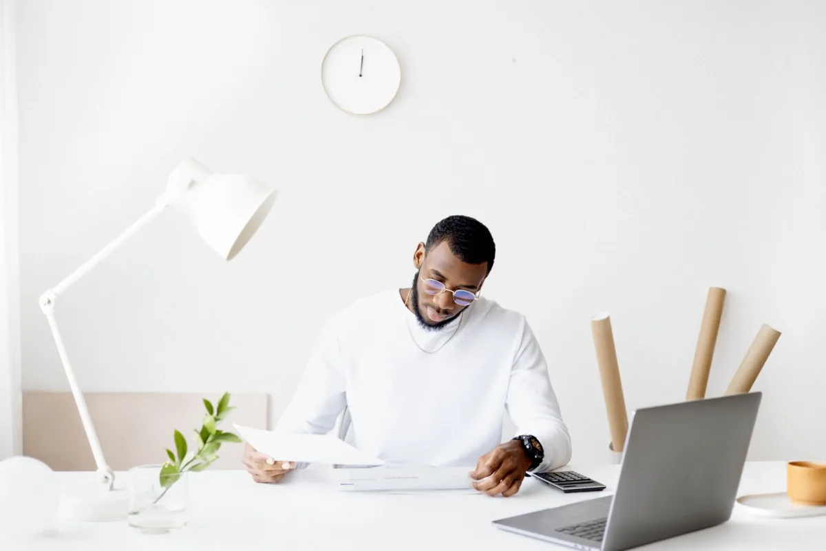 Business owner reviewing paperwork at a desk with laptop and calculator