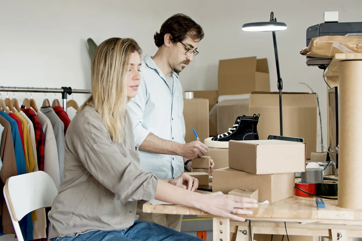 Two people packing products into shipping boxes