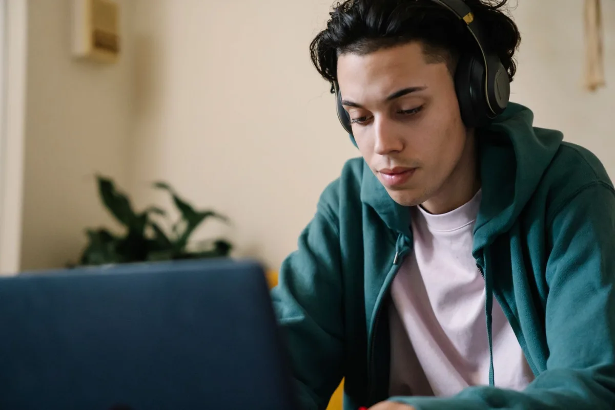 Mann mit Kopfhörern lernt konzentriert am Laptop zu Hause