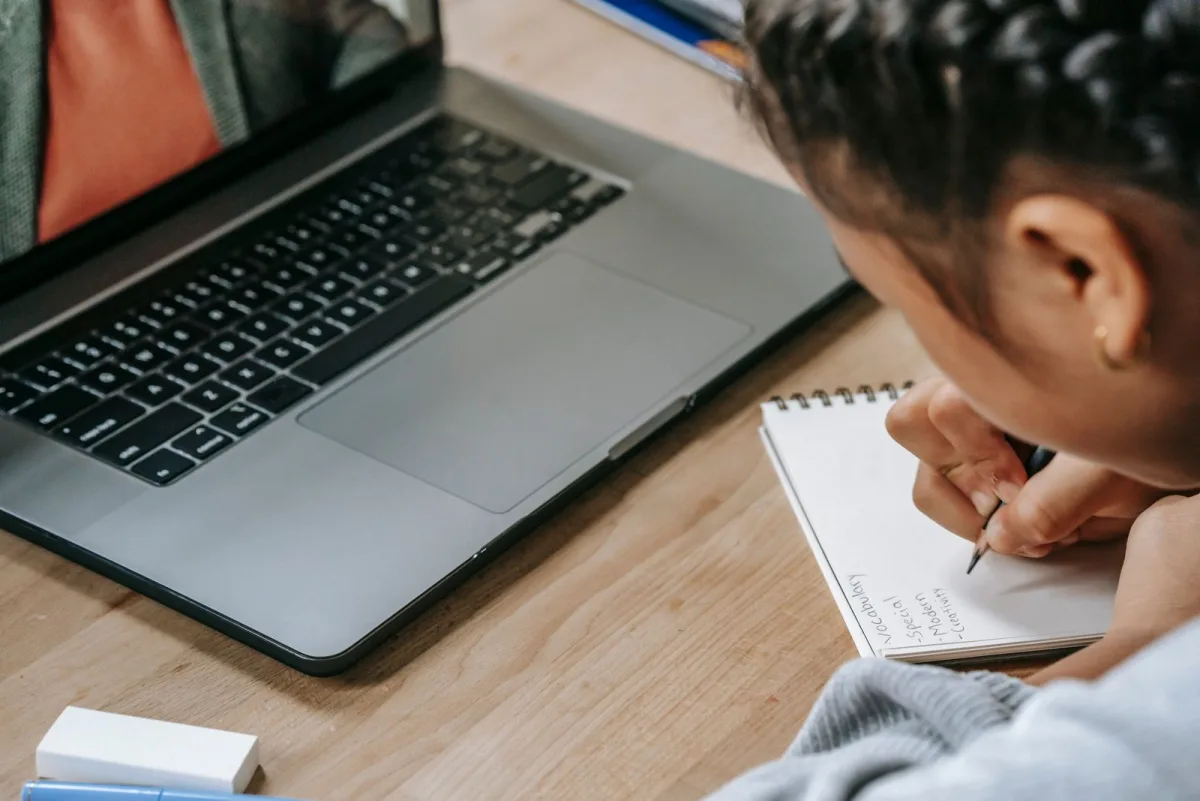 Lernende macht sich Notizen während eines Online-Kurses am Laptop