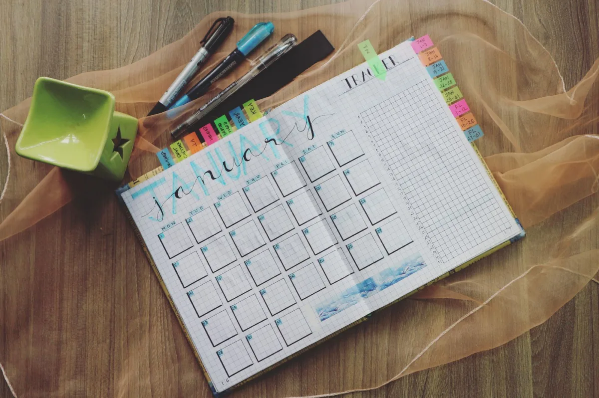 Aufgeschlagener Monatsplaner mit Kalender und Tracker zur Arbeitszeitplanung
