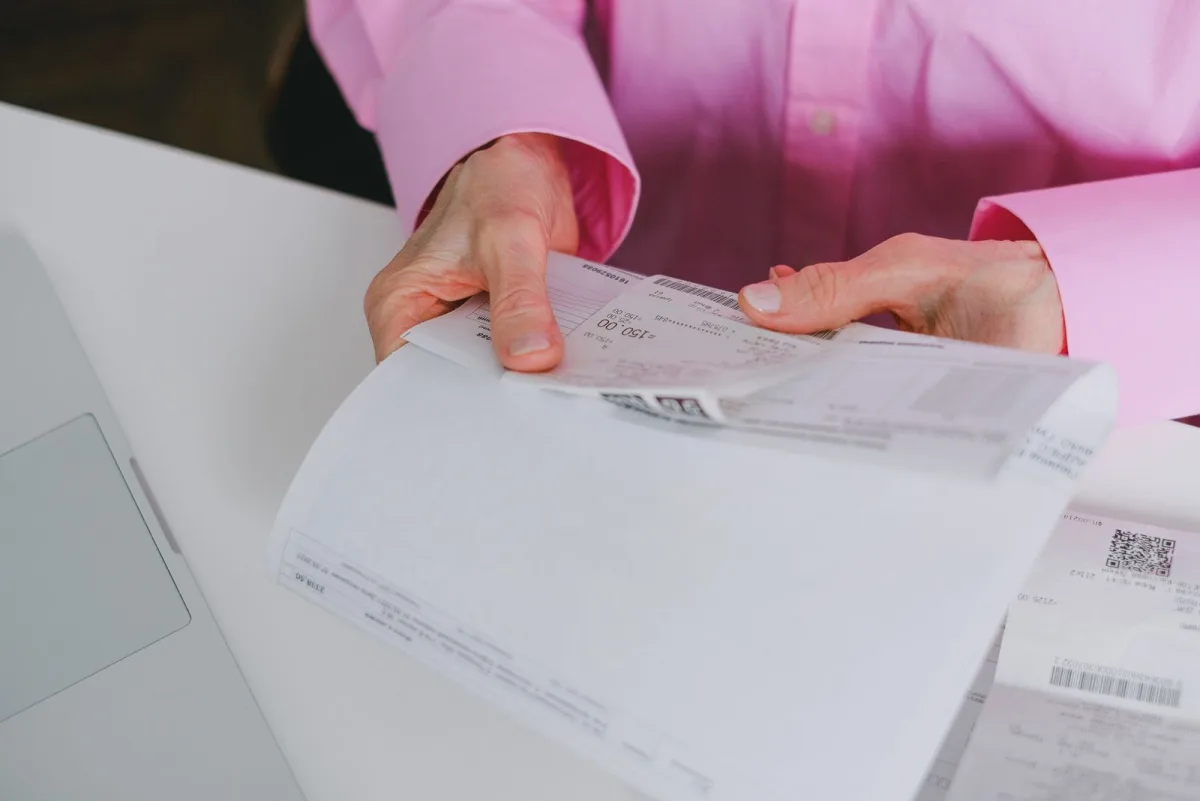 Hand hält einen Kassenbeleg zur Kontrolle der Einzelposten