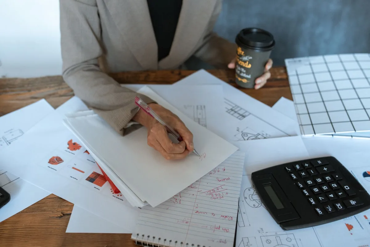 Person sketching content ideas while holding a cup of coffee