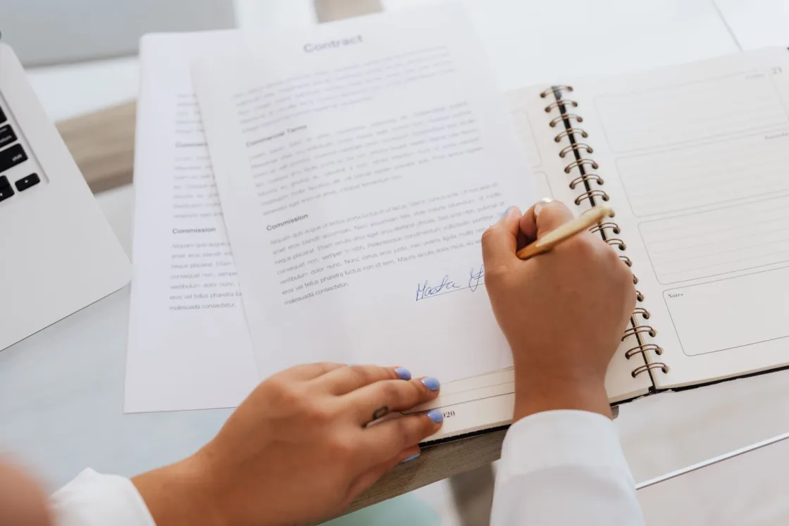 Person signing an employment contract at a desk