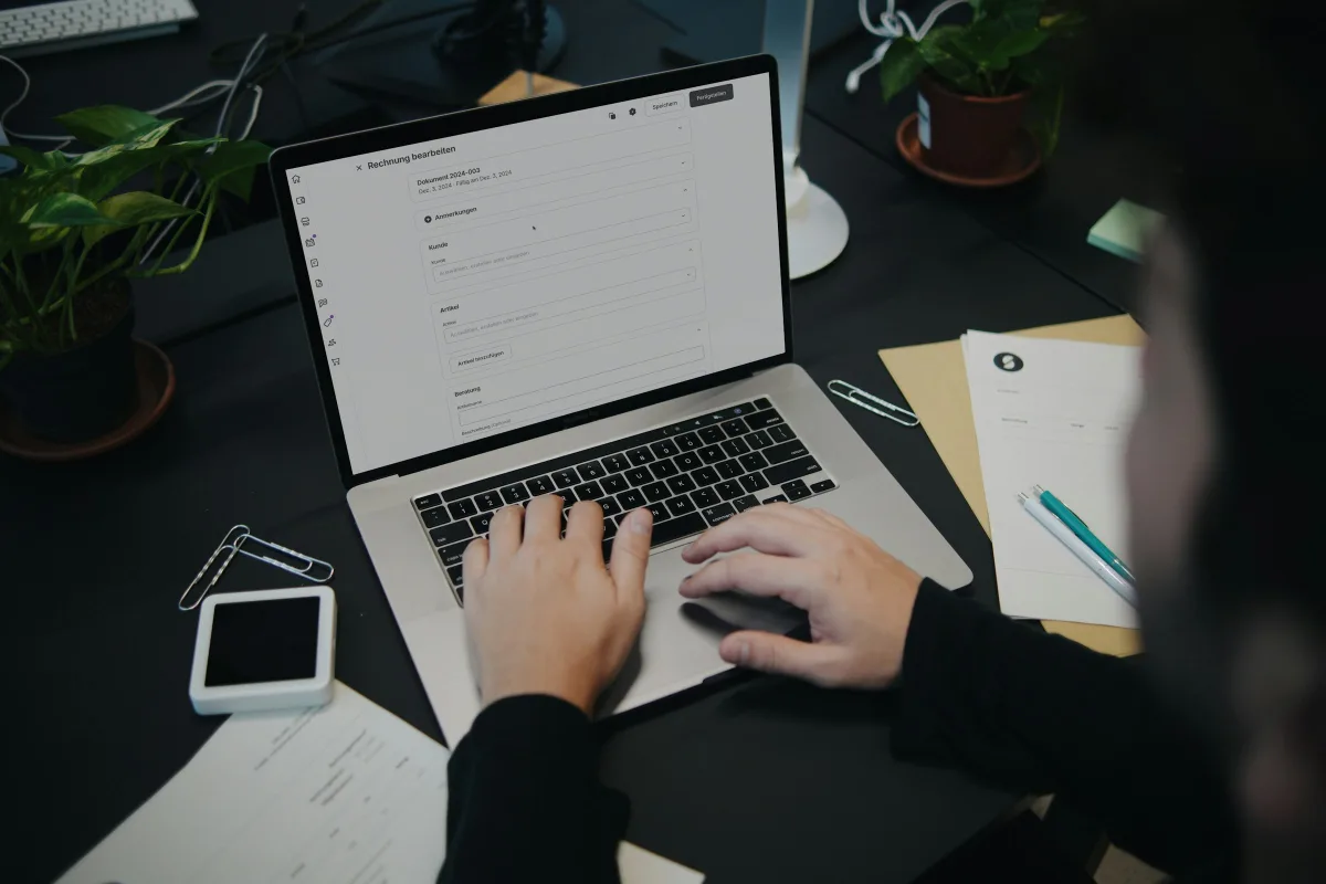 Eine Person sitzt am Schreibtisch und nutzt einen Laptop