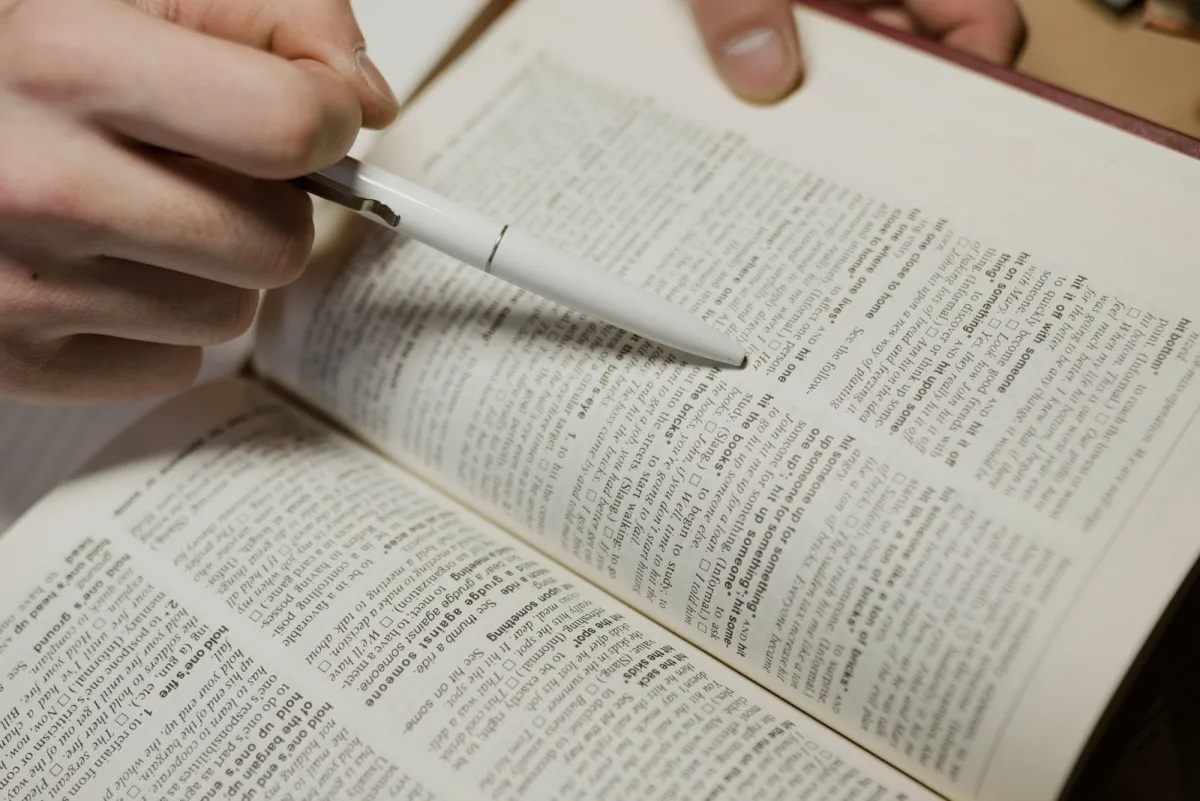 Editor pointing a pen at an entry in a reference book