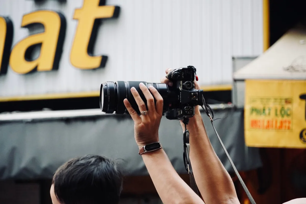 Freelance photographer raising a camera with a telephoto lens during an assignment
