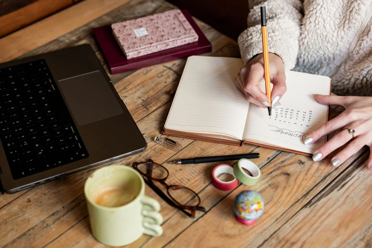 Woman writing a skill inventory list in a notebook at her desk