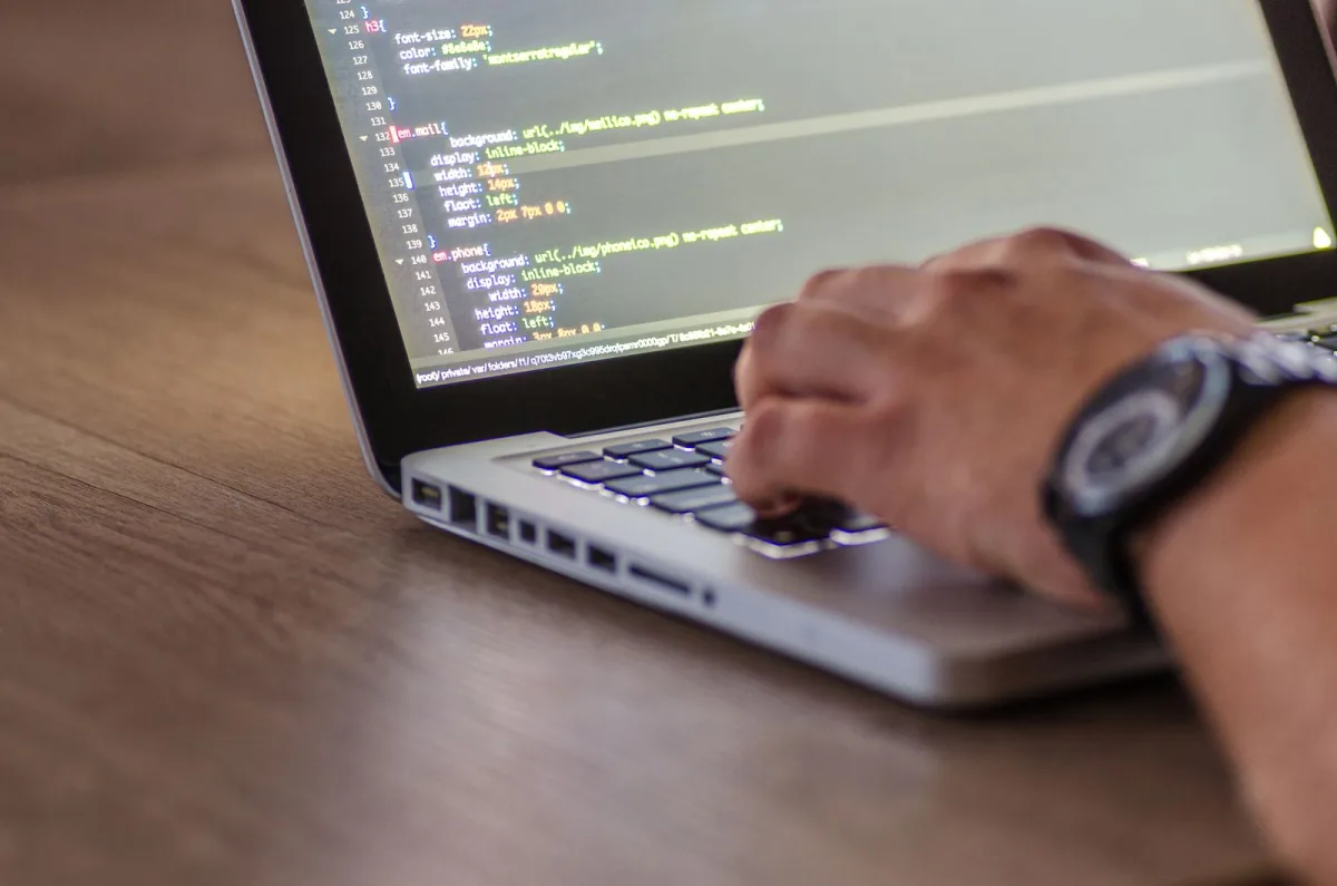 Laptop mit geöffnetem Code-Editor auf einem Schreibtisch