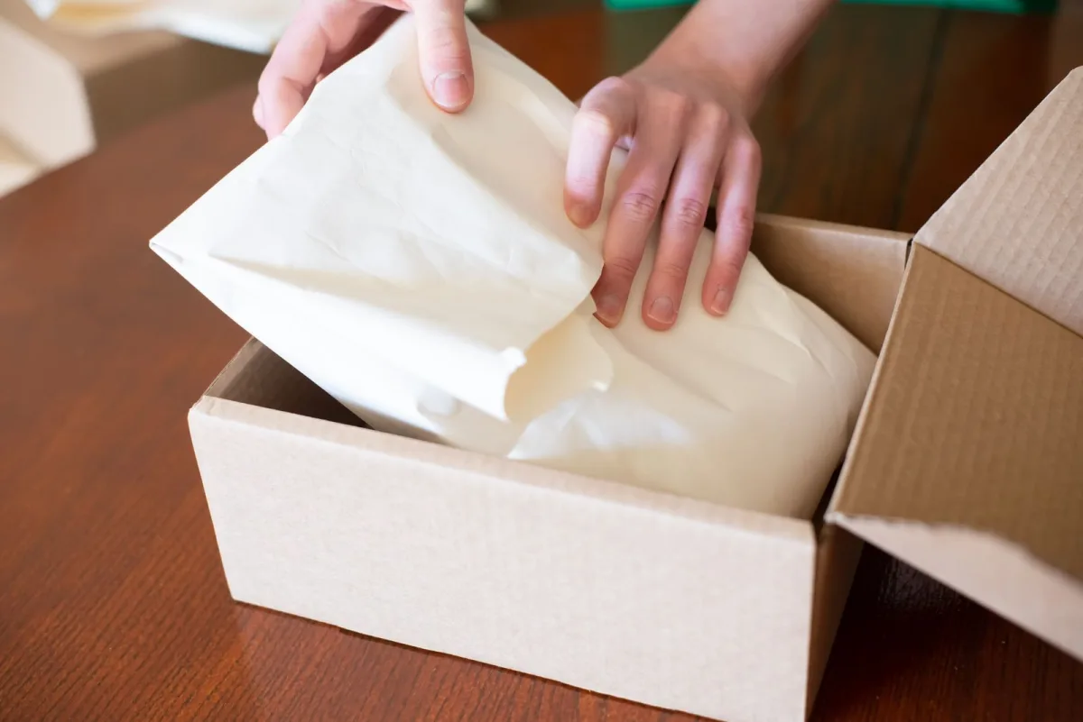Hands packing an order into a cardboard box for shipping