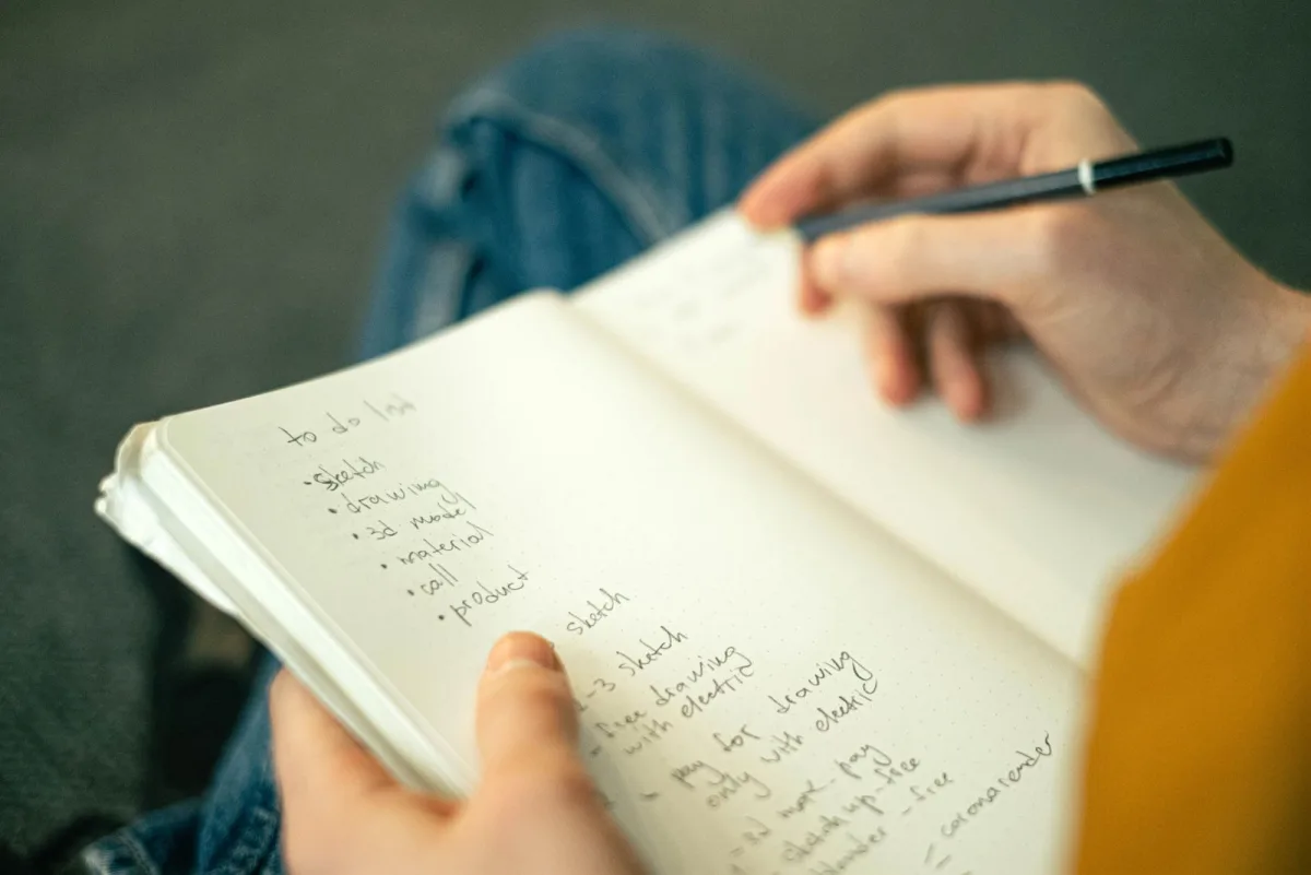 Person writing a to-do list in a notebook