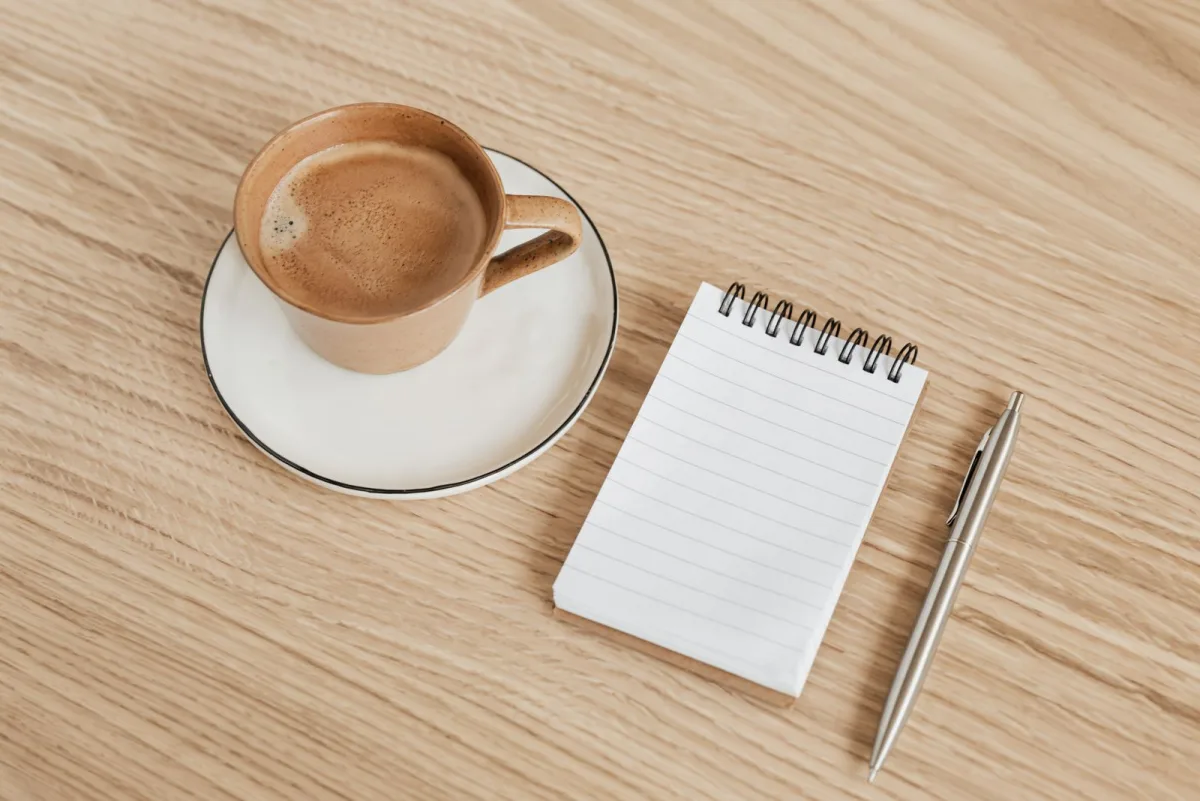 Notizbuch mit Stift und Kaffee auf einem Holztisch