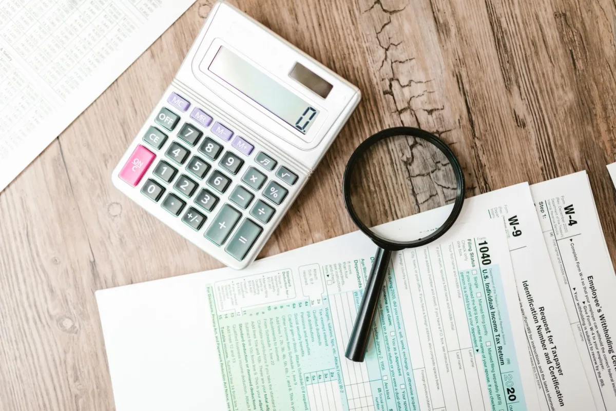 Taschenrechner und Lupe liegen auf Finanzunterlagen