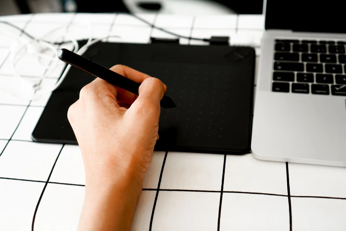 Grafikdesigner arbeitet mit Stift und Grafiktablett am Schreibtisch