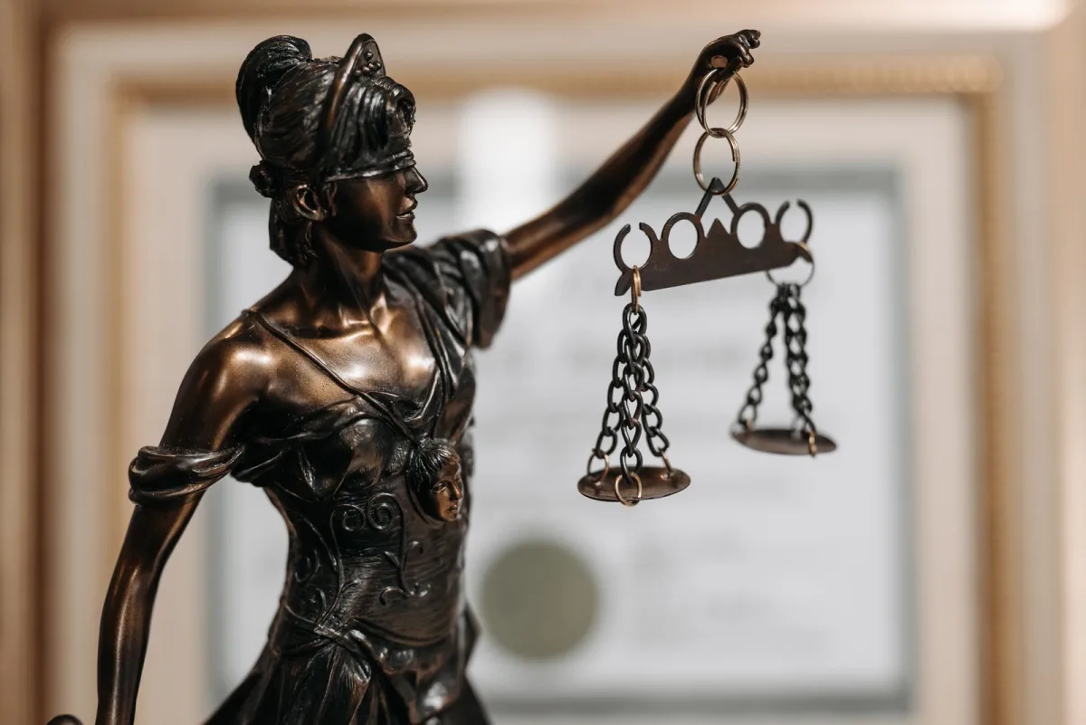 Justitia-Figur mit Waage auf einem Schreibtisch in einer Kanzlei