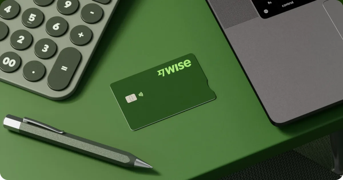 Green Wise Business debit card on a desk next to a laptop, calculator and pen